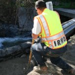 Slurry cement poured near a bridge that contains a water pipe is smoothed out.