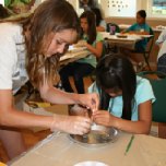 Caroline Werth, 14, is a former camper-turned Junior Naturalist. She assists Allyson Asis, 8, in dissecting an owl pellet.