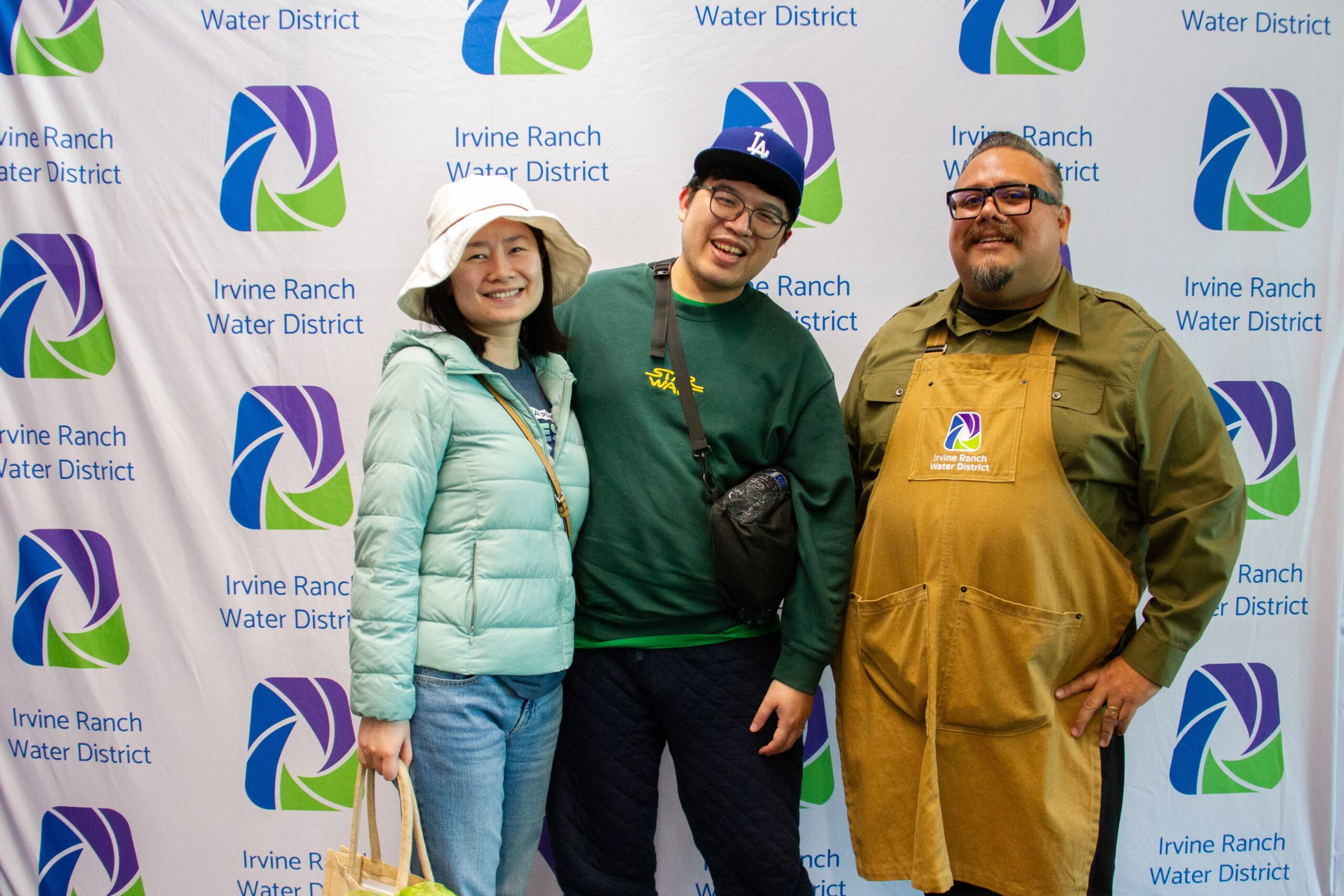 Three people pose in front of an Irvine Ranch Water District backdrop with logos.