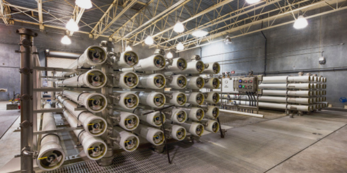 Industrial storage area with stacked horizontal cylindrical pipes on metal racks in a factory