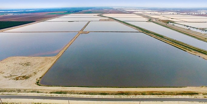 An aerial view of large rectangular salt ponds separated by earthen berms and roads.