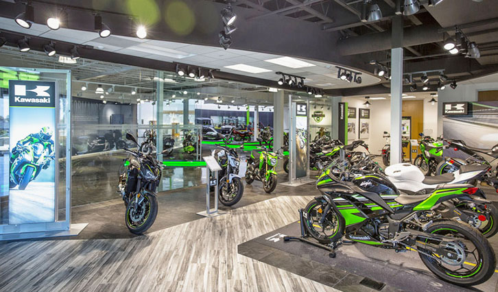 Kawasaki showroom with multiple green-and-black sport bikes on display inside a modern space.