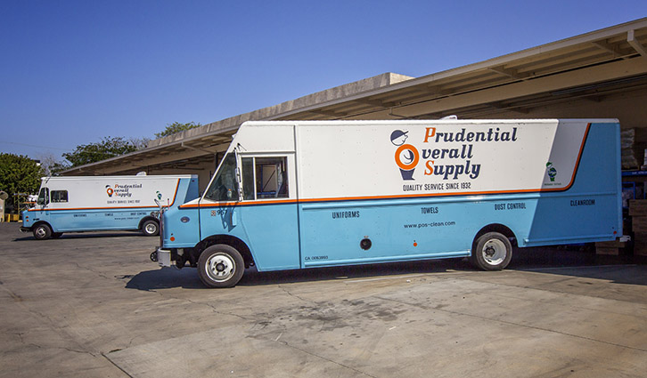A white-and-blue Prudential Overall Supply service truck parked at a loading dock.