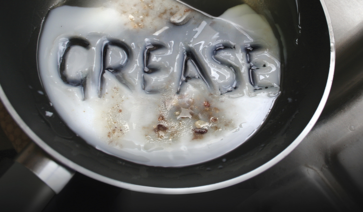 Frying pan with melted white grease spelling the word GREASE on the surface.