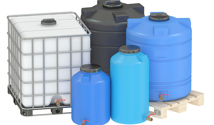 IBC tote and multiple plastic drums on a pallet for bulk liquid storage.