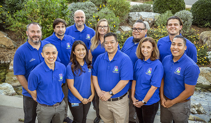 Group of diverse professionals in matching blue polo shirts posing outdoors