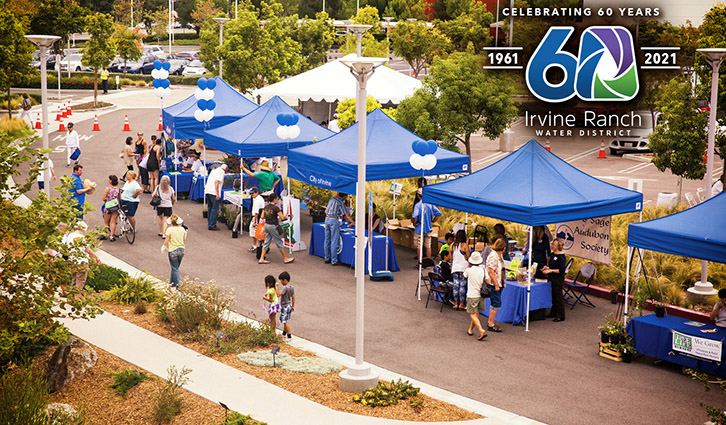 Outdoor community fair with blue tents, balloons and booths celebrating Irvine Ranch Water District's 60th anniversary.