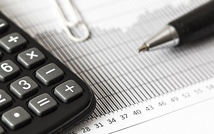 Close-up of a calculator on a printed financial document with a pen and ruler.