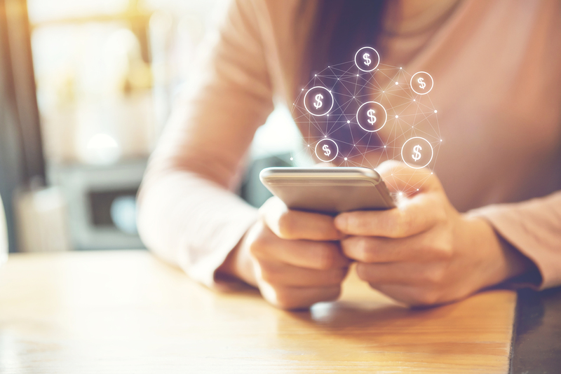 Person holding a smartphone with a glowing network of dollar icons around it.