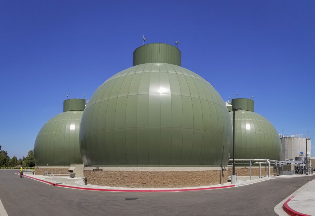 Cluster of large green spherical storage tanks at an industrial facility under a clear blue sky.