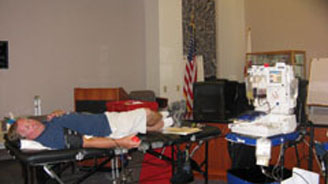 Man lying on a medical cot in a room with an American flag, beside a tall medical device.