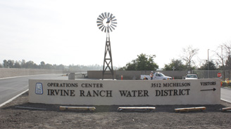 Sign for Irvine Ranch Water District Operations Center with a tall windmill sculpture in a desolate gravel lot.