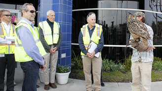 Group of people wearing high-visibility vests touring a modern building exterior.
