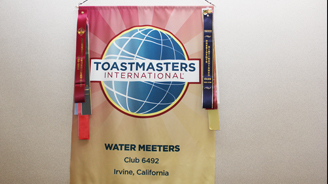 Toastmasters International banner with globe logo and colorful ribbons, displaying Water Meeters Club 6492, Irvine, California.
