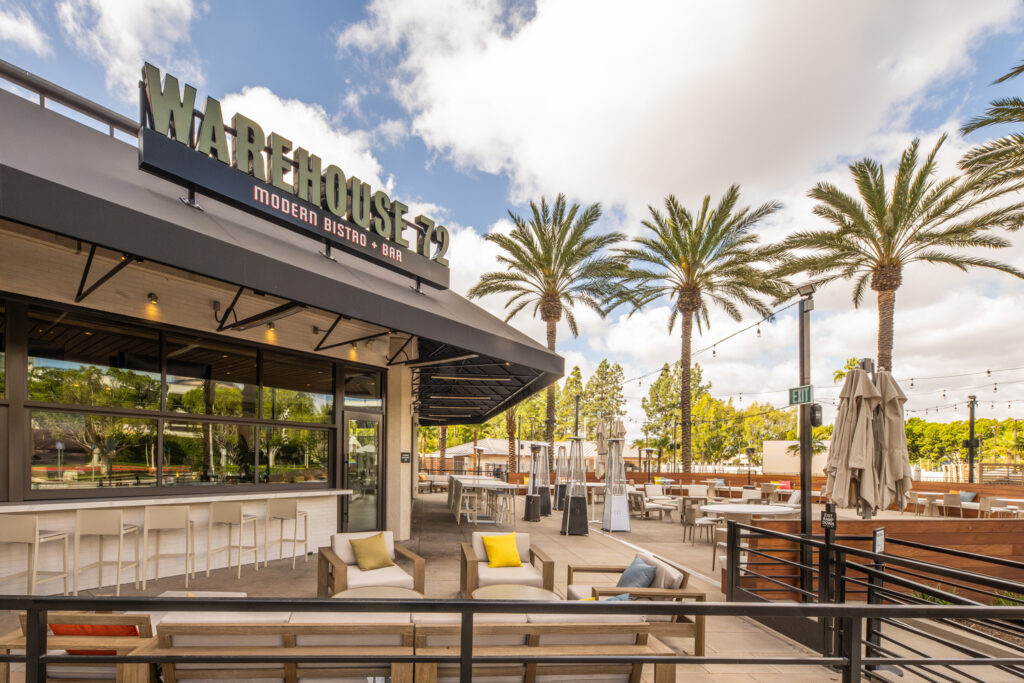 Warehouse 72 Modern Bistro + Bar exterior with outdoor seating, palm trees, and string lights.