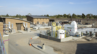 Active construction site with brick buildings, scaffolding, and utility installations under a clear blue sky.