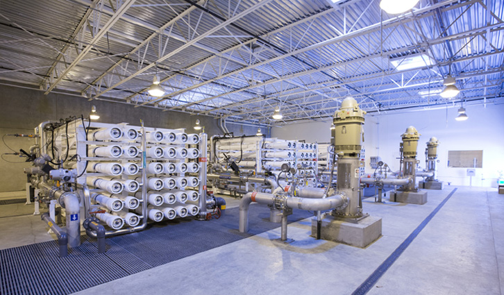Industrial water treatment plant with rows of membrane cartridges, pipes, and large pumps.