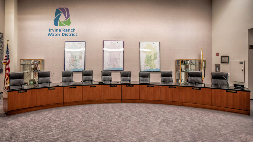 Irvine Ranch Water District boardroom with a curved wooden conference table, executive chairs, and maps on the wall.