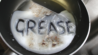 White waxy substance in a frying pan with the letters GREASE formed on its surface.