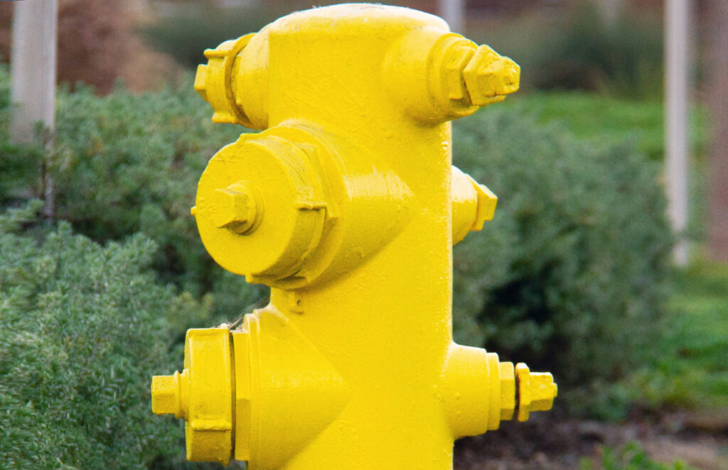 Close-up of a bright yellow fire hydrant with exposed bolts and four outlets.