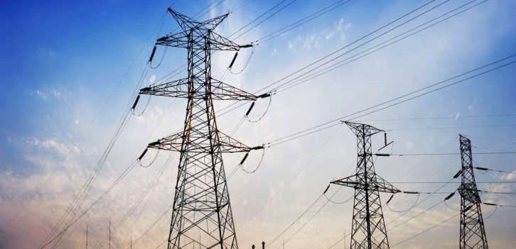 High-voltage transmission towers and power lines stretching across a blue sky.