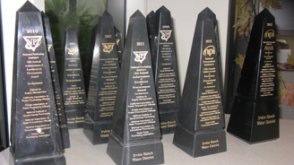 Row of black obelisk trophies with gold lettering and logos.