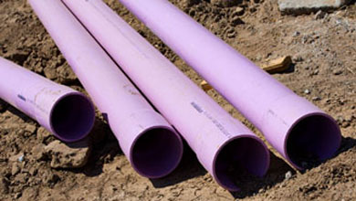 Purple PVC pipes lying on dirt at a construction site