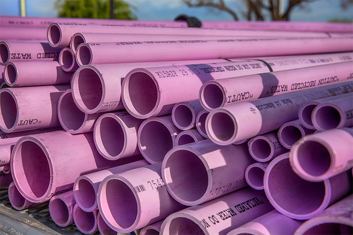 Pink PVC pipes stacked in a construction site.