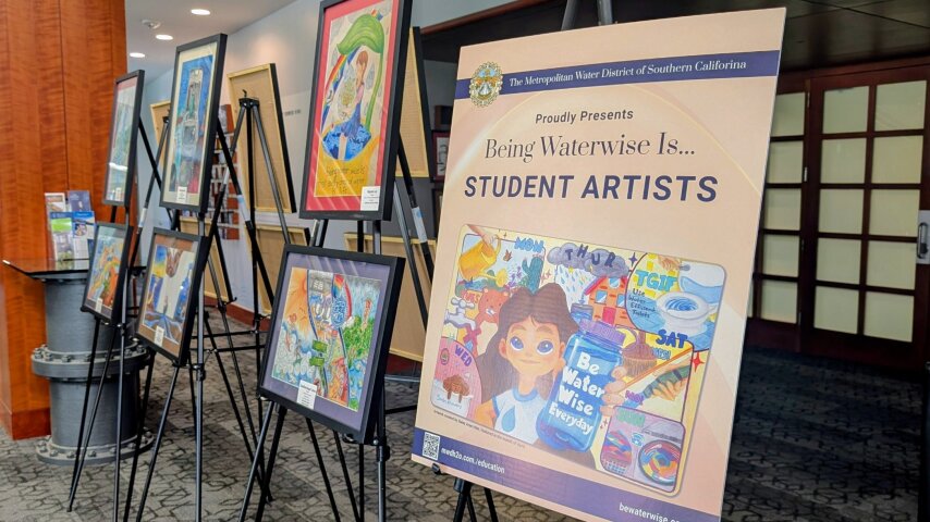 Display of student artworks on easels next to a poster titled Being Waterwise Is... Student Artists.