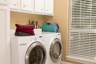 Stacked front-loading washer and dryer in a laundry room with folded towels on top