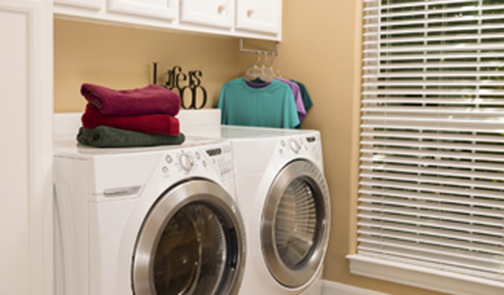 Front-loading washer and dryer in a bright laundry room with folded towels on top.